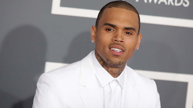 Chris Brown on the red carpet, wearing a white suit and looking off to the side