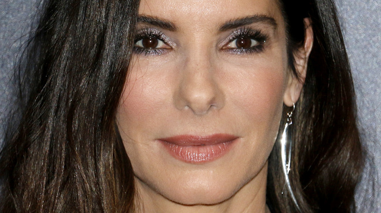 Sandra Bullock wears glitter eyeshadow and silver drop earrings at an event