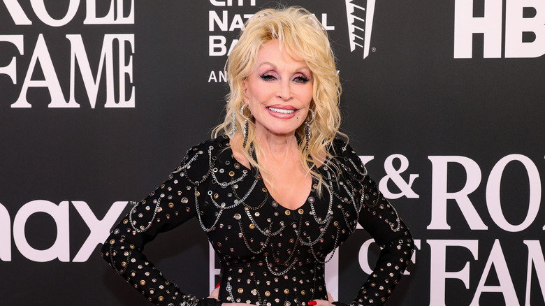 Dolly Parton posing in a black dress with grommets and chains