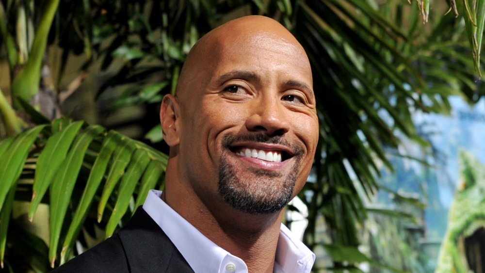 Dwayne 'The Rock' Johnson smiling in front of palm tree