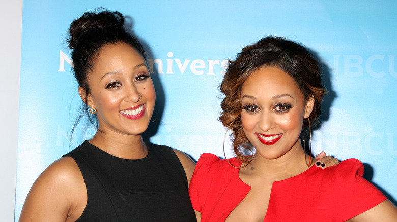Tamera Mowry-Housley and Tia Mowry-Housley smile on red carpet