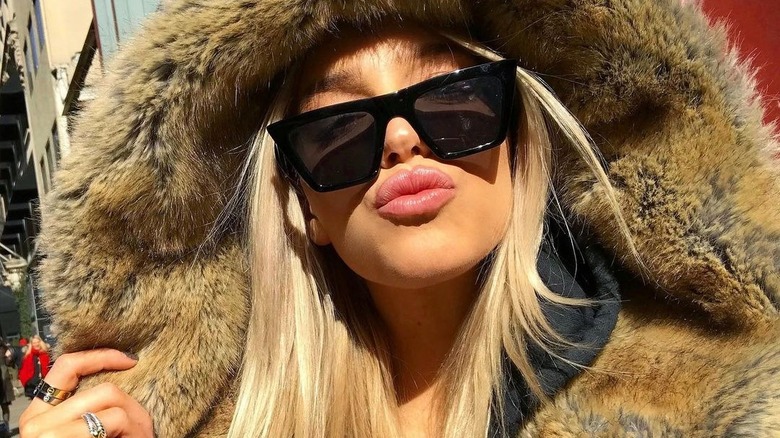 Alex Cooper taking a selfie in a fur coat