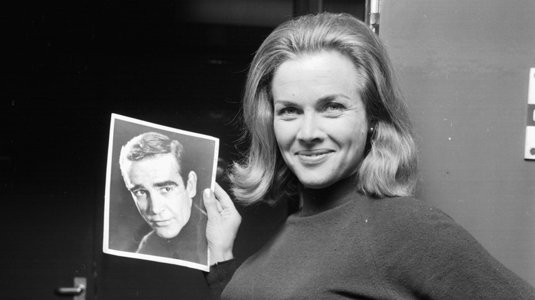 Honor Blackman posing with photo of Sean Connery
