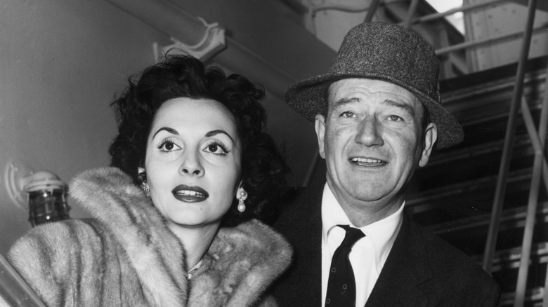 John Wayne and Pilar Pallete posing for photos on a ship