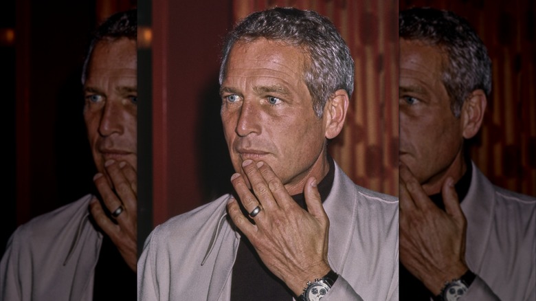 Paul Newman pictured touching his face at an event.