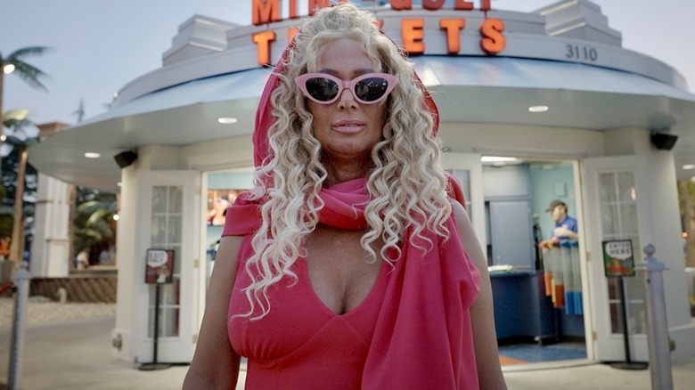 Tonia Haddix posing in front of a restaurant in pink cat-eye sunglasses