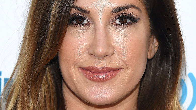 Jacqueline Laurita smiles while wearing a black blouse and natural makeup