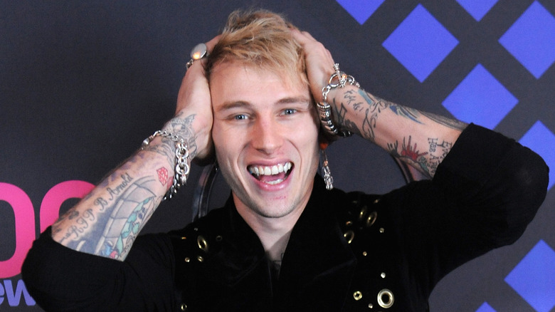 Machine Gun Kelly with hands on head