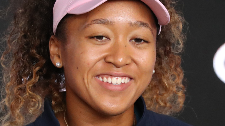 Naomi Osaka smiling and wearing pink visor