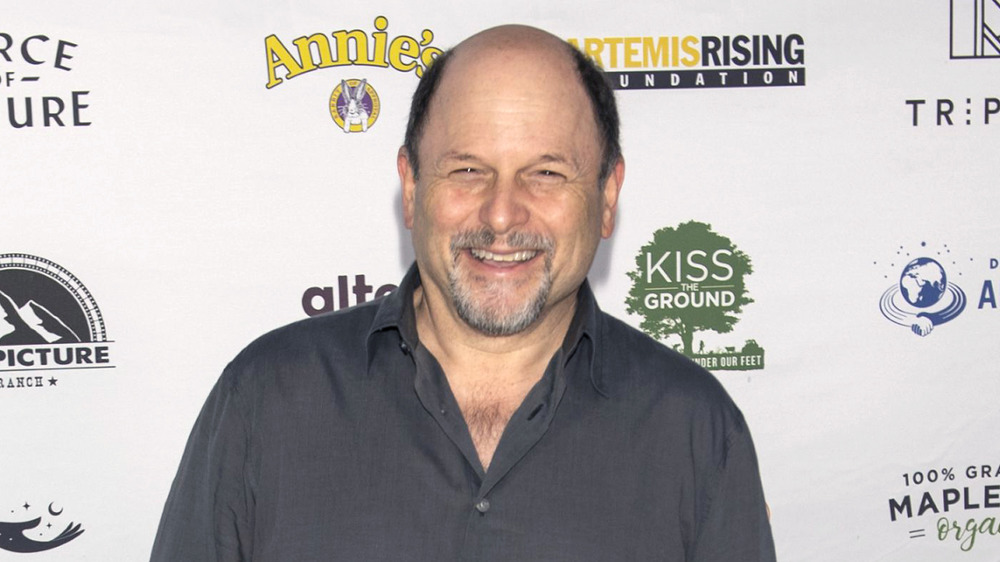 Jason Alexander smiling while posing for cameras