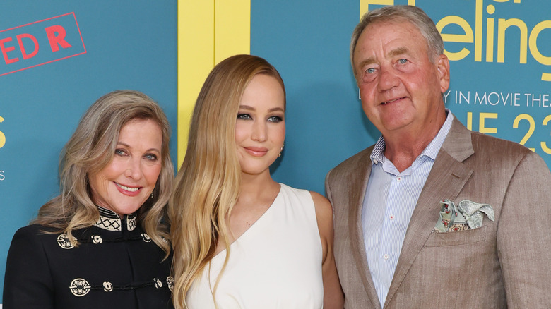 Karen Lawrence, Jennifer Lawrence, and Gary Lawrence smiling and posing on the red carpet