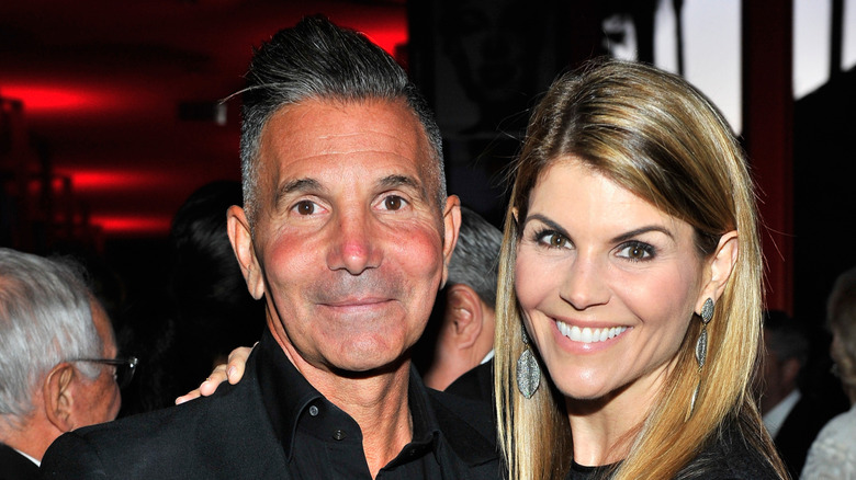 Lori Loughlin smiles and poses with a hand on Mossimo Giannulli's shoulder in 2015.