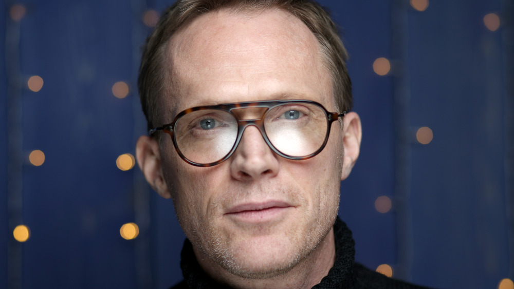 Paul Bettany looks into the camera wearing rimmed glasses