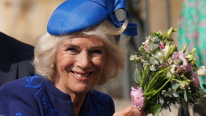 Queen Camilla smiles holding a bouquet