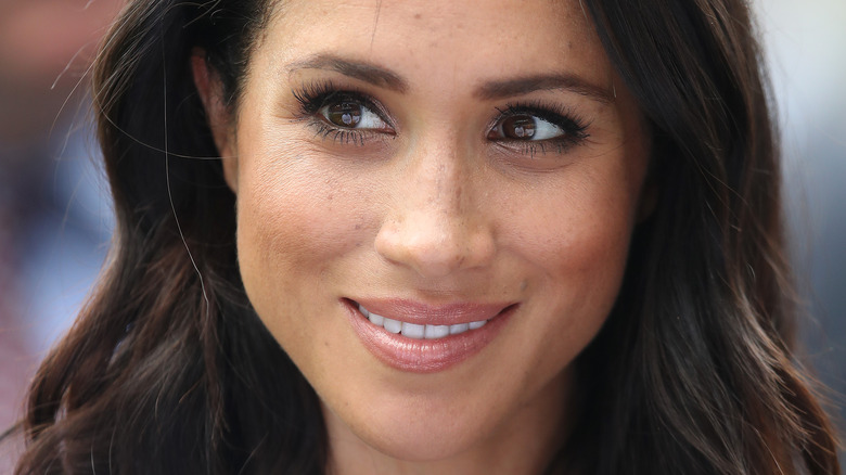 Meghan Markle smiling and looking to the side