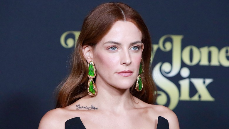 Riley Keough long drop green earrings center part hair