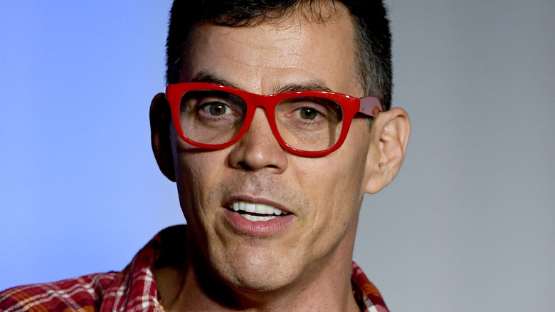 Steve-O, 2020 event, wearing red glasses, no facial hair, talking, looking serious 