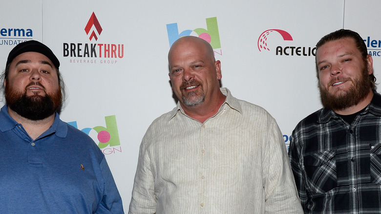 Austin Russell, Rick Harrison, and Corey Harrison posing in front of a step and repeat