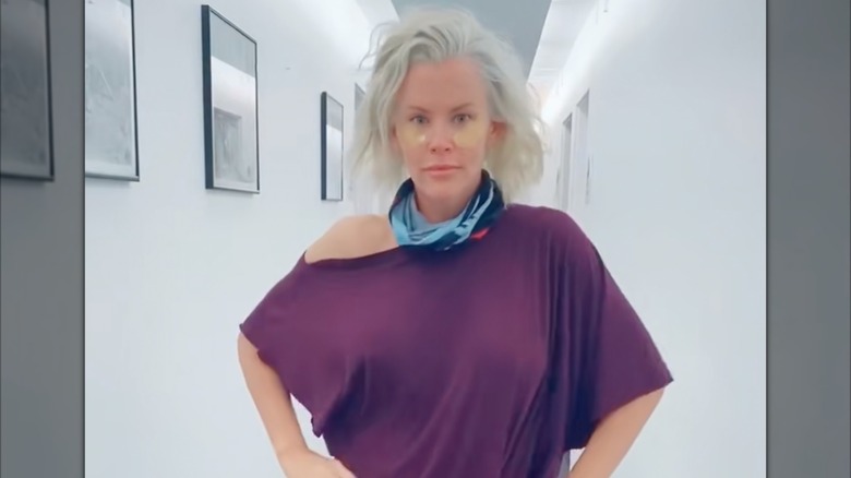 Jenny McCarthy wearing no makeup and eye patches while standing in a brightly lit, white hallway