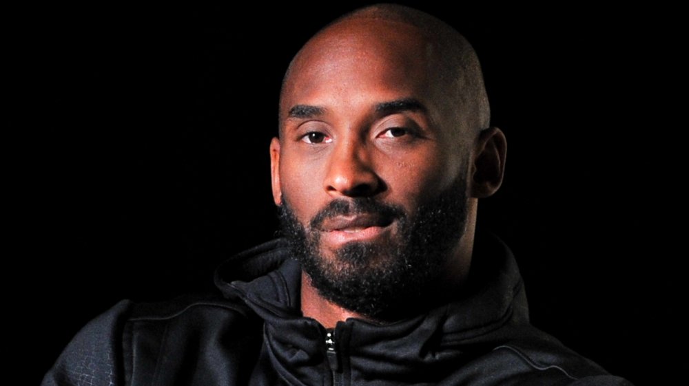 Kobe Bryant in a black jacket looking at camera