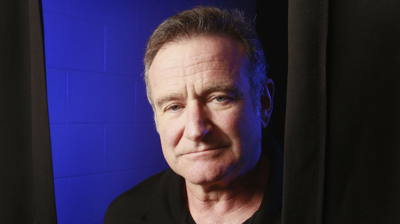 Robin Williams looking sad next to a curtain