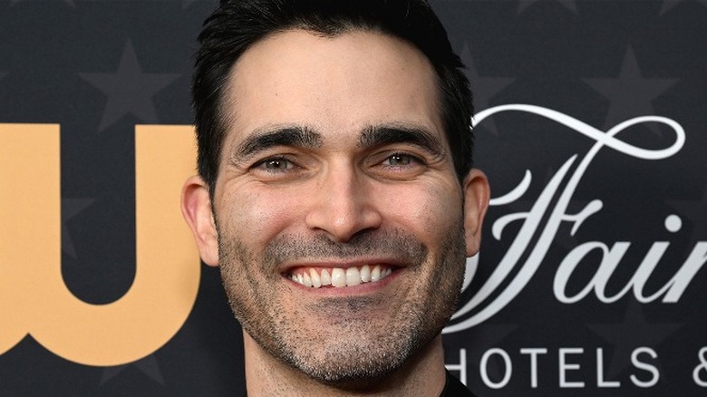 Tyler Hoechlin smiling black bacground CW logo