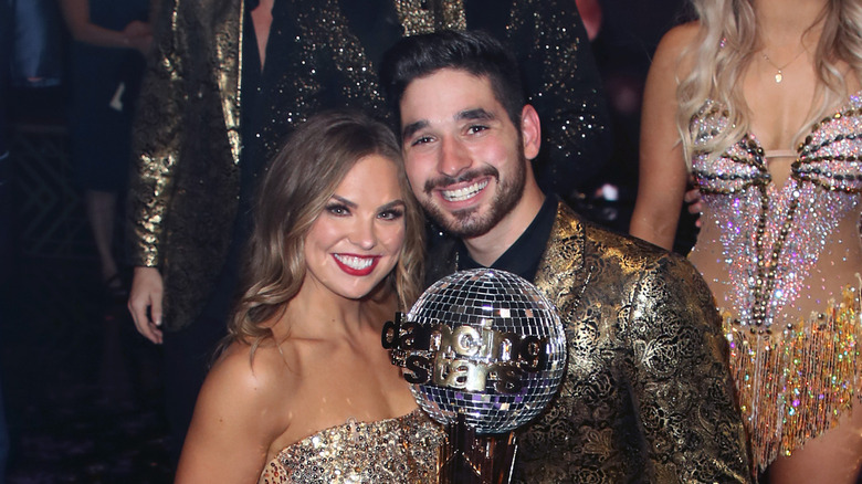 Hannah Brown and Alan Bersten smiling and posing with the Mirrorball Trophy.