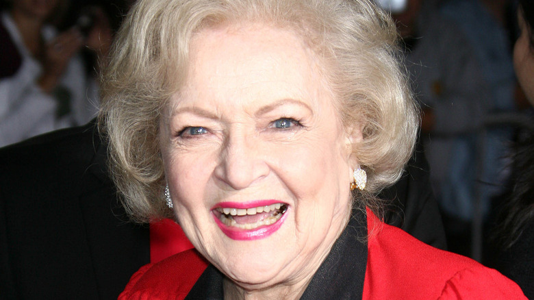 Betty White smiles in a red outfit