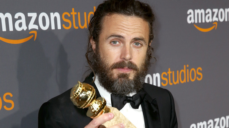 Casey Affleck holding Golden Globe
