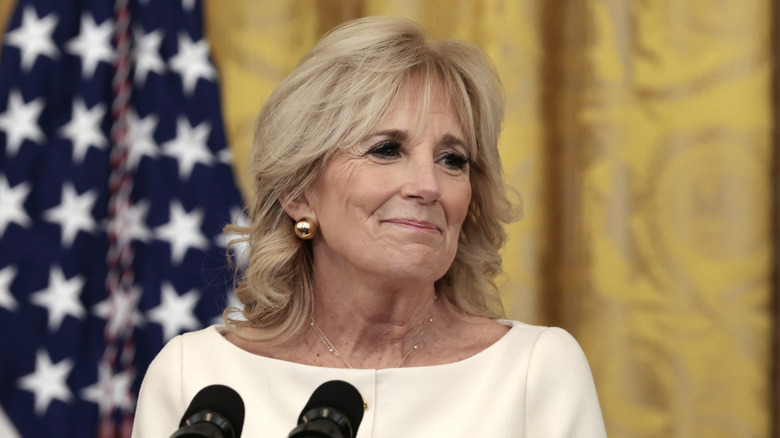 Jill Biden smiles at the audience while standing by a microphone