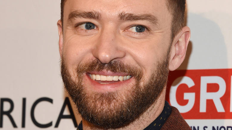 Justin Timberlake smiles in a maroon suit
