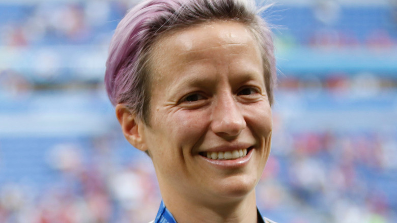 Megan Rapinoe, smiling, pink short hair, on the soccer field, 2019 photo