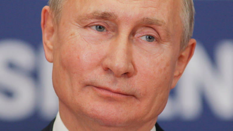 Vladimir Putin looks on with a dark suit