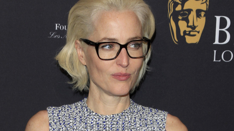 Gillian Anderson pursing her lips and wearing black glasses