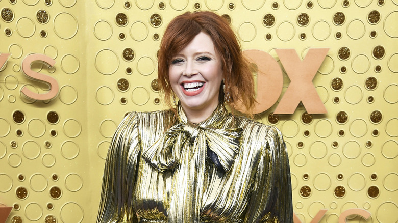 Natasha Lyonne laughing in gold dress