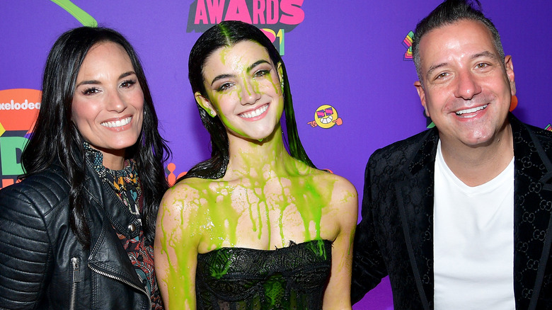 Carli D'Amelio with green slime on her, posing with parents