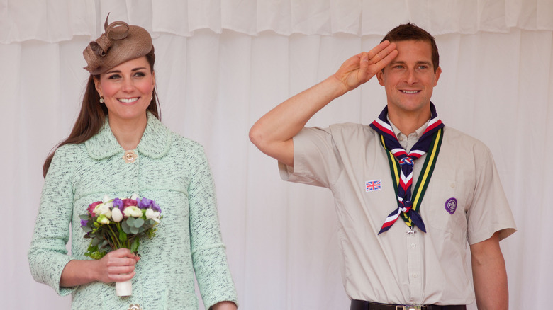 Bear Grylls saluting, standing next to Kate Middleton