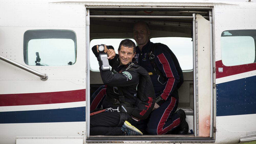 Bear Grylls in a plane, posing with his phone