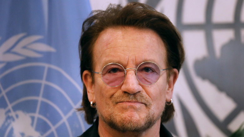 Bono posing in front of the United Nations flag