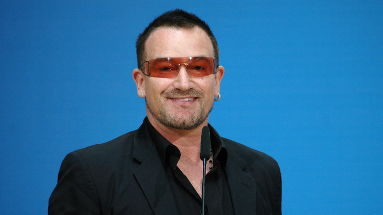 Bono wearing sunglasses in front of a mic