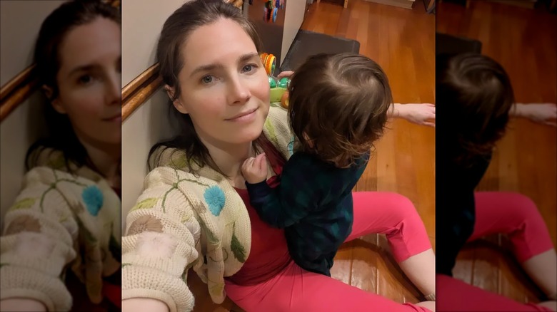 Amanda Knox seated on the floor and taking a selfie with her son