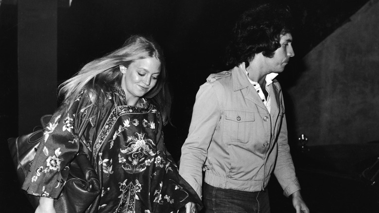 Goldie Hawn and Bill Hudson walking hand in hand.