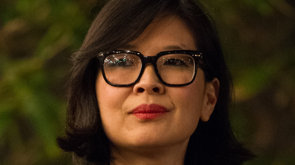 SuChin Pak listening and wearing thick, black-rimmed glasses