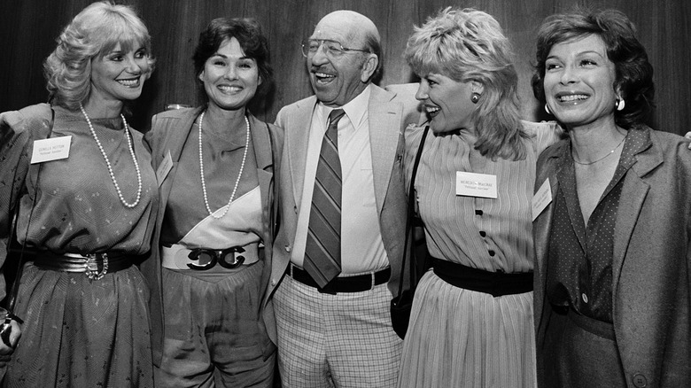 A black and white photo of Frank Cady laughing with his arms around several cast members