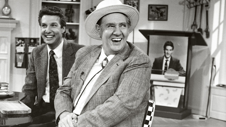 A black and white photo of Pat Buttram laughing with another man sitting behind him