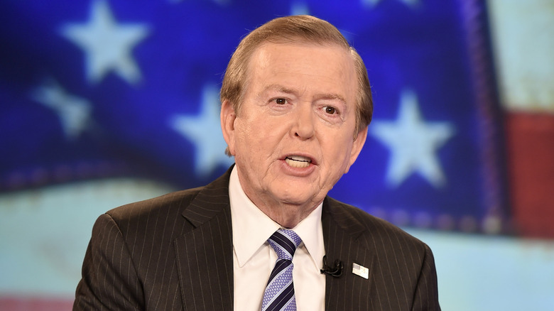 Lou Dobbs in front of an American flag on the set of his Fox Business show
