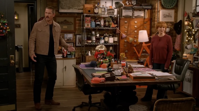 Steve Howey stands across from Reba McEntire and gestures with his hands.