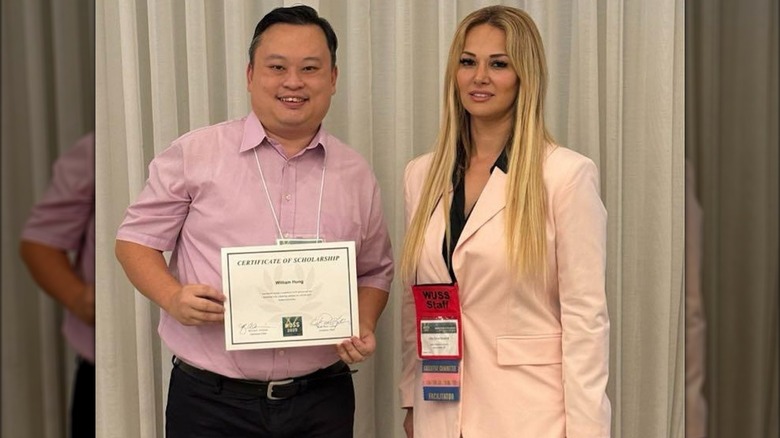 A smiling William Hung displays his certificate while standing next to a WUSS official.