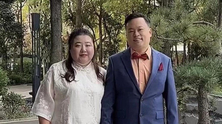 William Hung and Hannah Du are all smiles on their wedding as they pose against a lush green background.