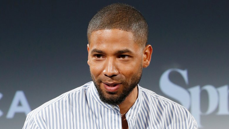 Jussie Smollett speaking at an event, with a smirk
